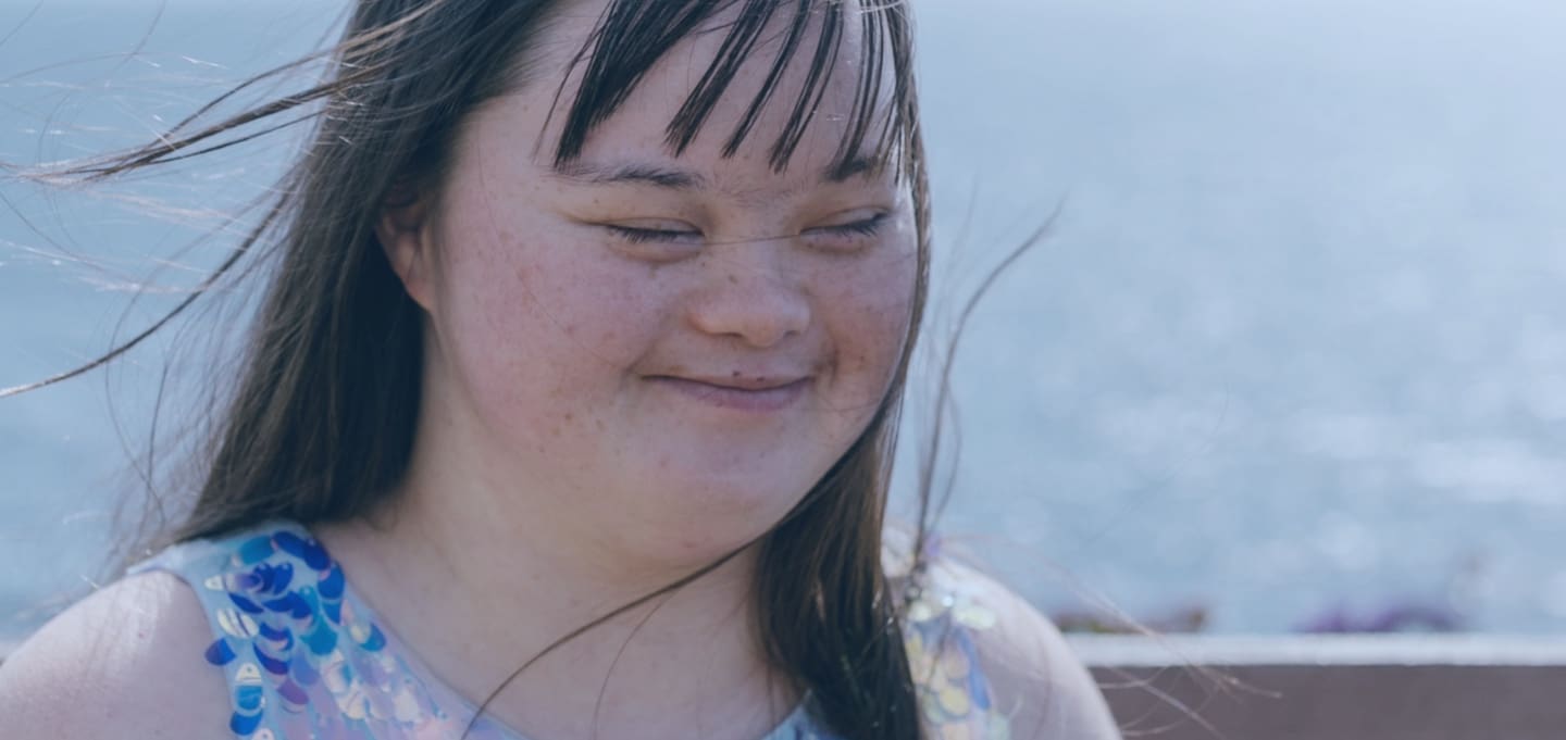 Girl smiling on a sunny, windy day | Special Journeys | Vacations for People with Disabilities
